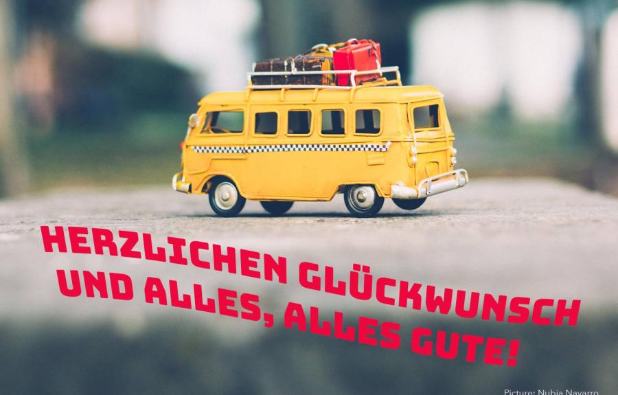 Caravan with luggage on top. Wavy German text: Herzlichen Gluckwunsch und Alles, Alles Gute!
