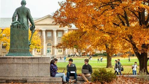 Students study near the statue of Ezra Cornell on the Arts Quad in fall. Students gathered next to the Ezra Cornell statue.