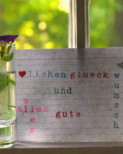 Vase and index card with German text in front of window